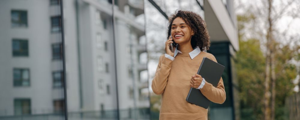 A woman walking outside on a VoIP business call using her mobile device.